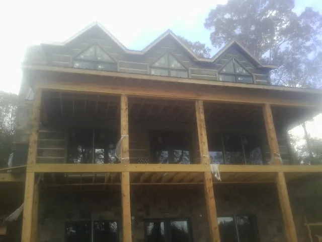 Dormers and porch framing on a large log home under construction — Roof Coating work by our crew in Lone Tree